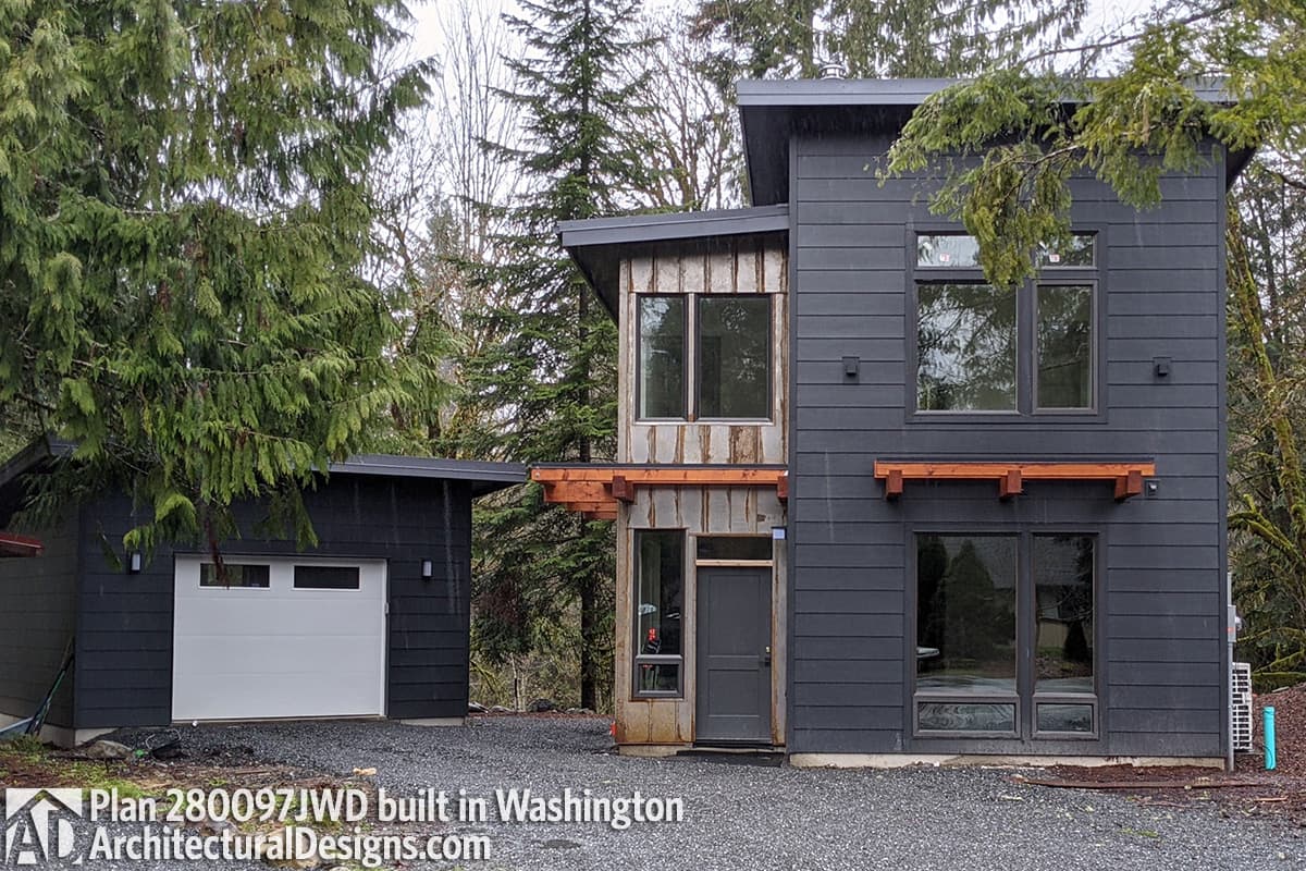 Modern house plan exterior with dark siding, metal accents, wood trim, and attached garage. Two stories with a flat roof.