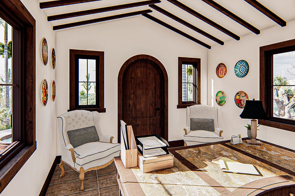 Interior view of a study with arched wooden door, built-in shelves, decorative plates, and two wingback chairs.