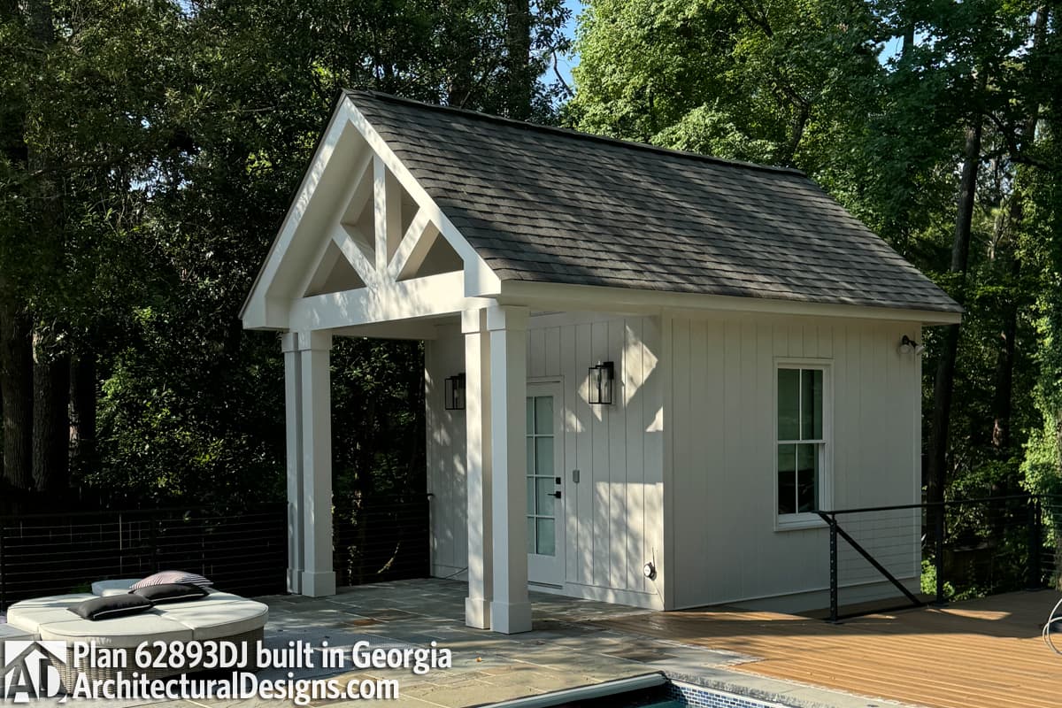 House plan exterior with a covered porch, gable roof with decorative trusses, and vertical siding.