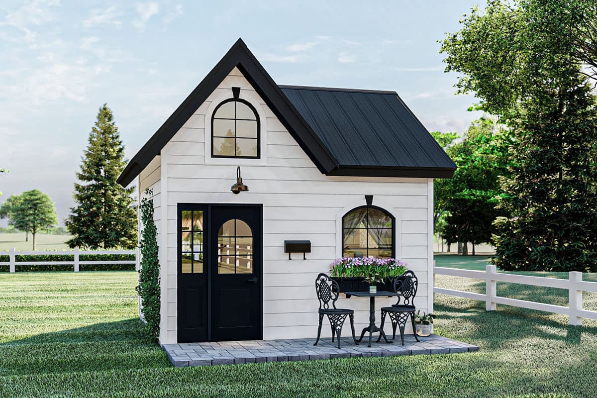 House plan exterior. Small, 1-story building with a black metal roof, gabled roofline, arched windows, and a black front door.