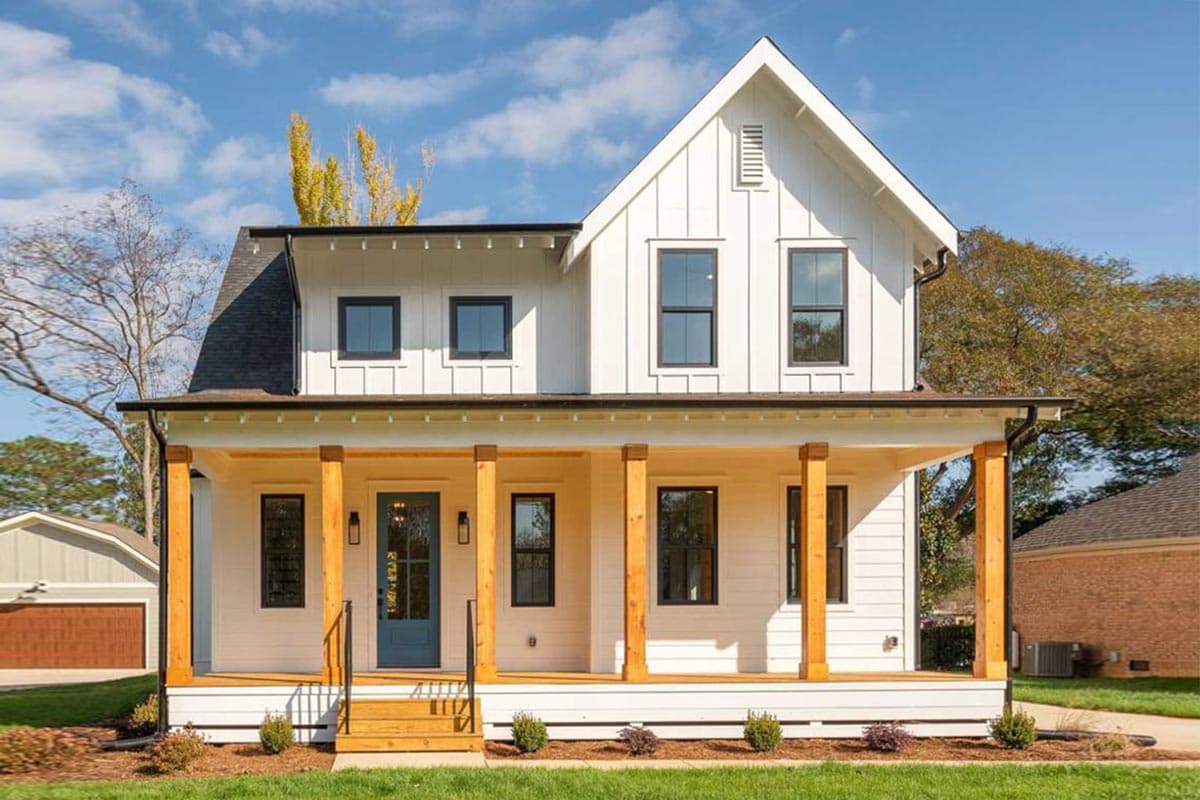 House plan exterior. Modern Farmhouse style, two-story home with a gabled roof and a covered front porch with exposed timber columns.