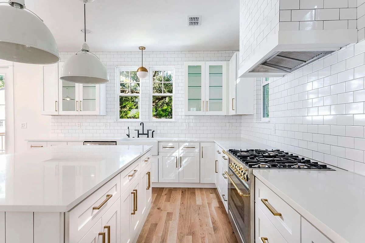 Modern kitchen with white subway tile backsplash, large island, gas range, and wood flooring.