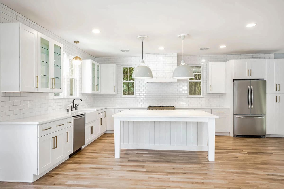 Modern kitchen with white shaker cabinets, subway tile backsplash, large island with seating, and stainless steel appliances.