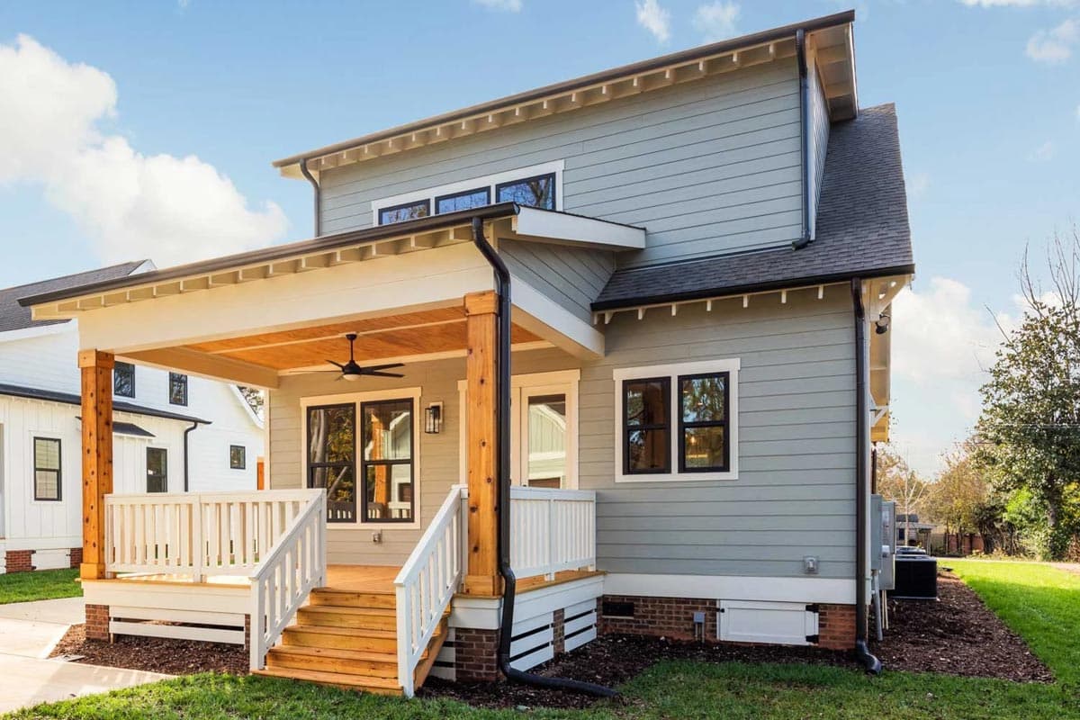 House plan exterior of a two-story home with a covered porch, wood-paneled ceiling, prominent timber supports, and visible gables.