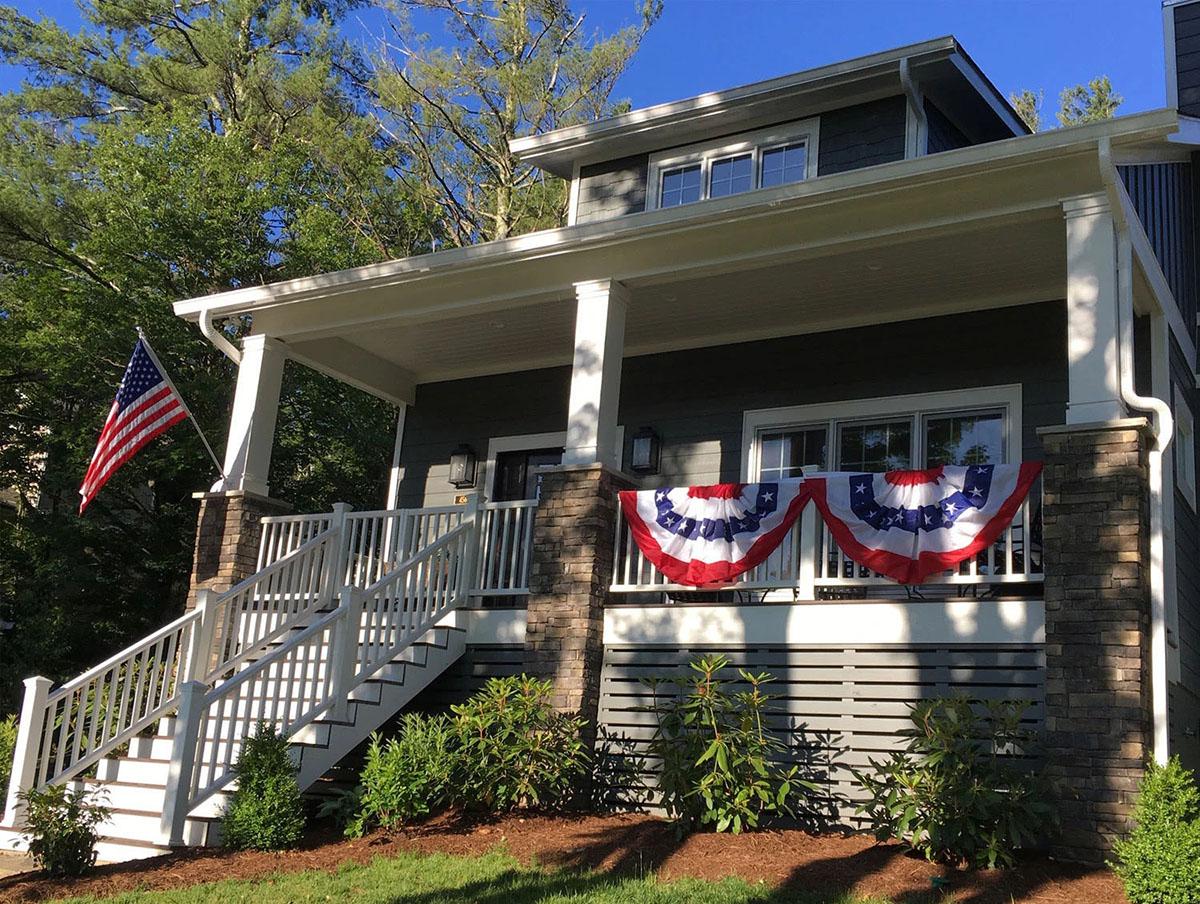 House plan exterior: Craftsman style, two stories, deep covered porch with stone accents, prominent front stairs, and dormer.