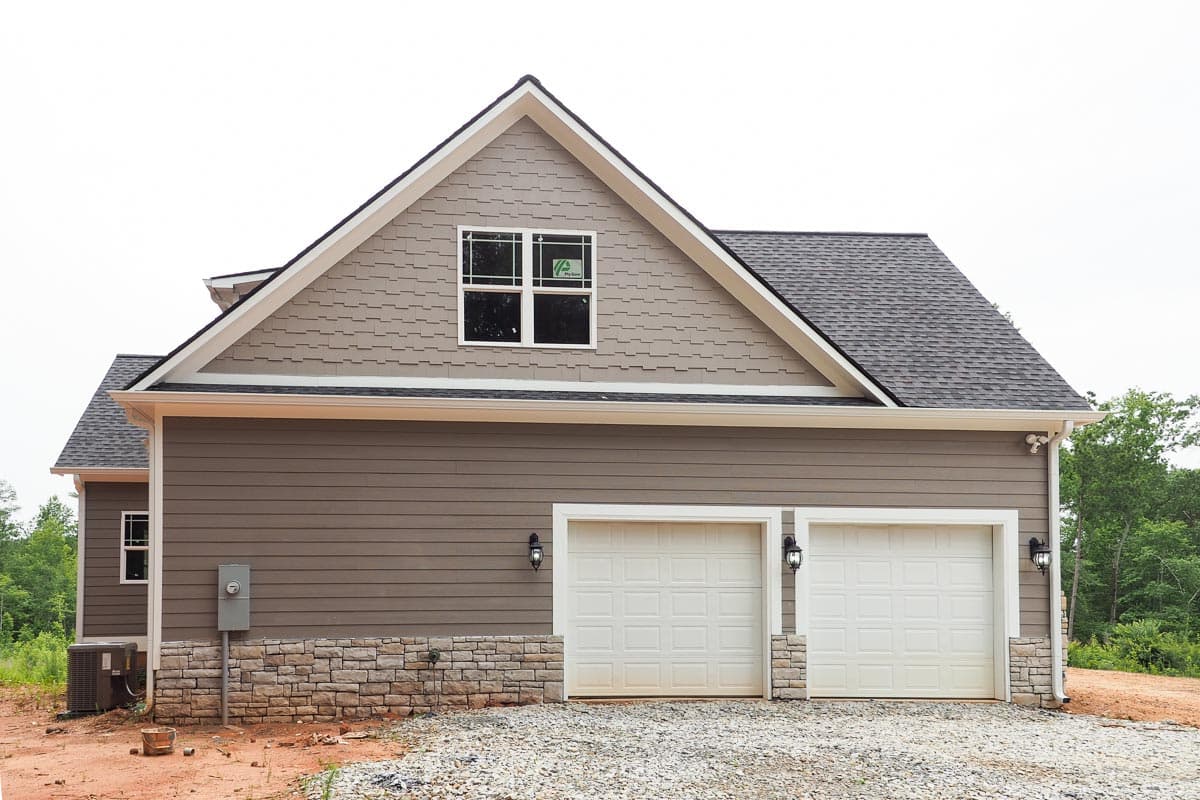 House plan exterior with horizontal siding, stone foundation, gable, dormer, and a three-car garage.