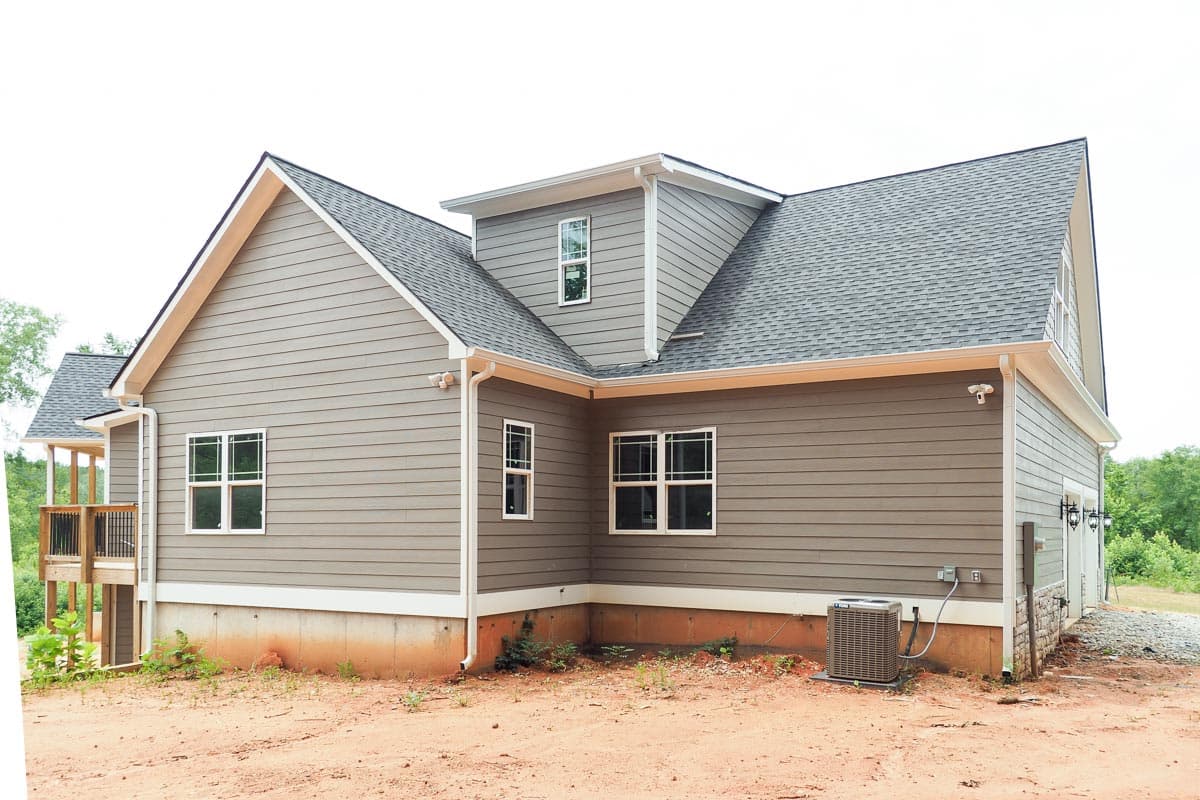 House plan exterior featuring horizontal siding, gabled rooflines, dormer windows, and a side-facing garage.