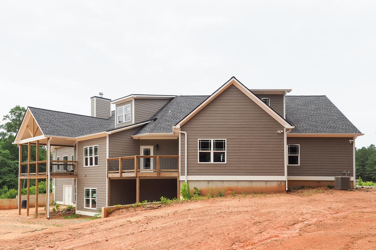 House plan exterior: two-story home with gabled dormers, multiple decks, and a prominent gabled roofline.
