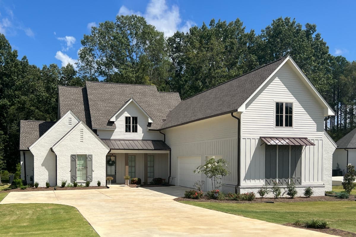 Modern Farmhouse house plan exterior with brick gable, white siding, dormers, and metal awnings over windows.