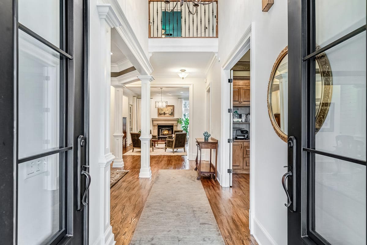 View from entryway into a house with a two-story hall, coffered ceiling, fireplace, and built-in cabinetry.