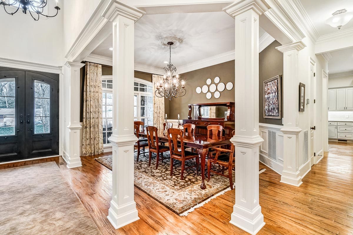 Interior view of a dining room featuring a table and chairs, ornate chandelier, and decorative molding.