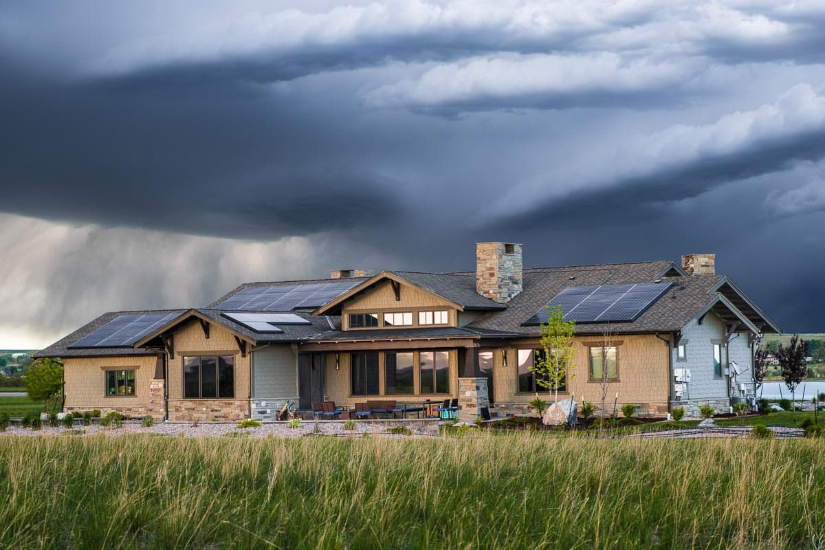 House plan exterior: Ranch style, single story with solar panels, stone chimney, and covered porch.