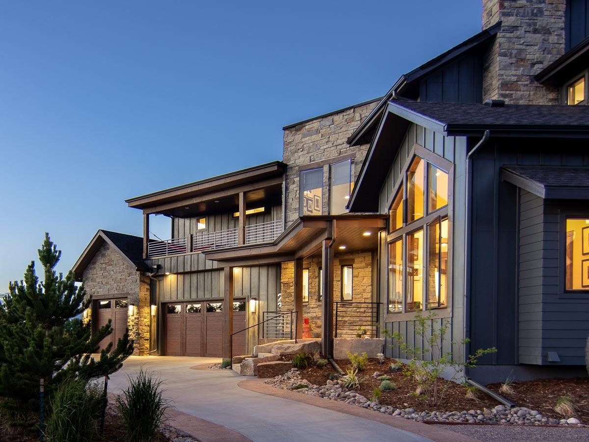 House plan exterior with stone and wood siding, multi-level rooflines, and a three-car garage.