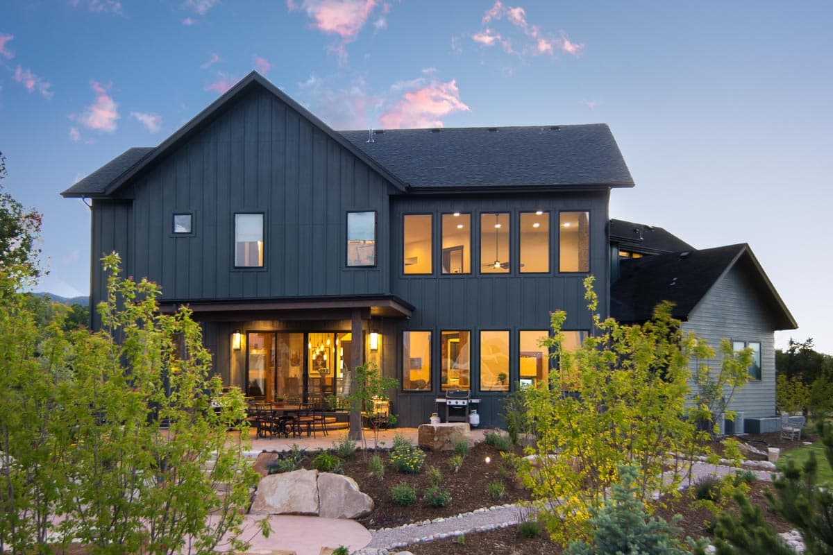 Modern house plan exterior with vertical siding, gabled roof, covered patio, and large windows.