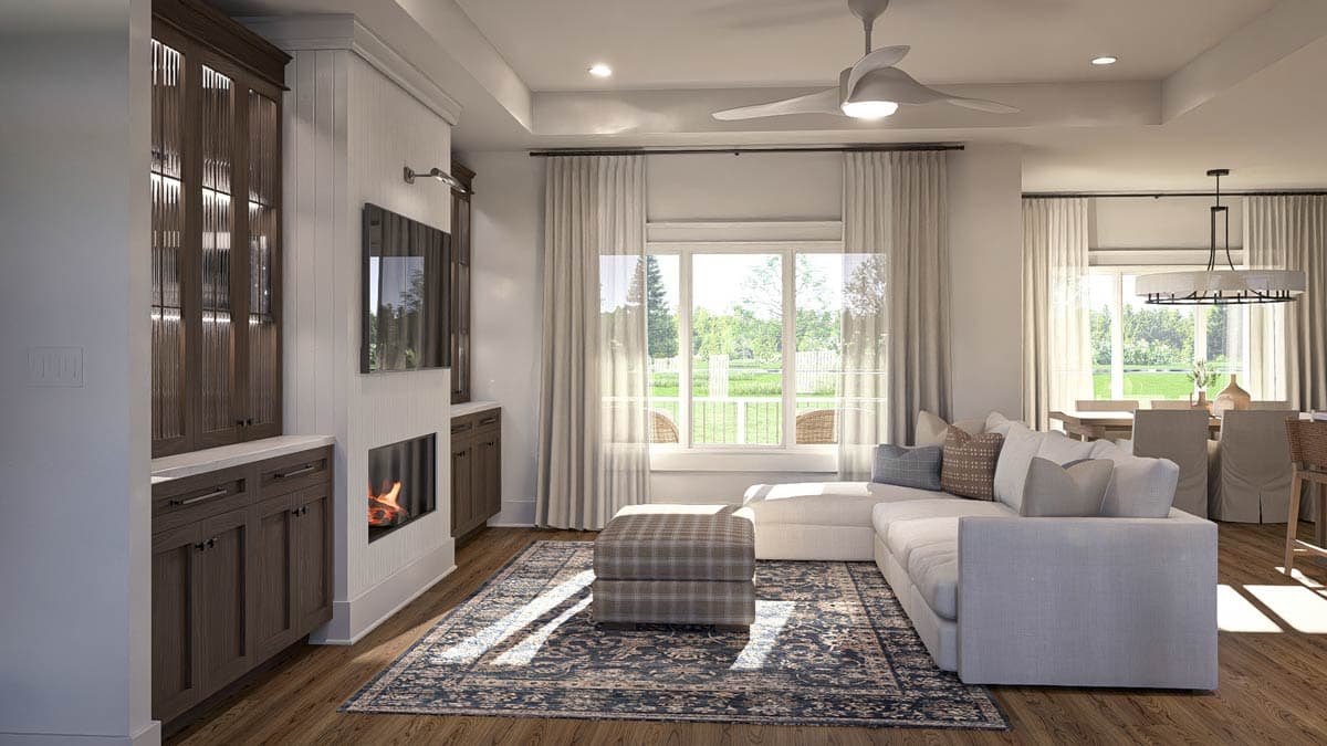 Living room with fireplace, built-in cabinetry, large window, sectional sofa, and dining area visible.