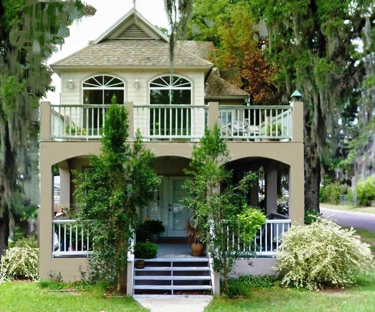 House plan exterior with two stories. Features include a front porch with arches, second-story balcony, and a gable roof with dormers.