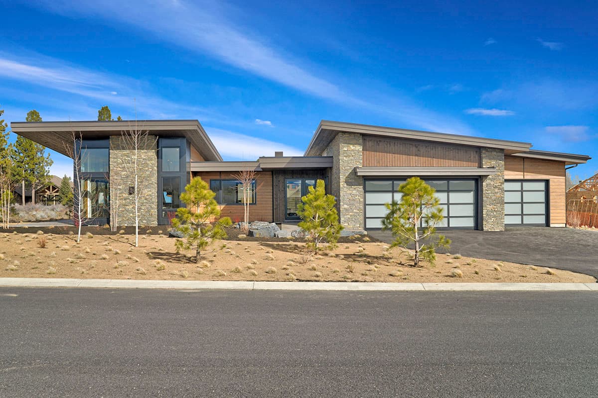 Modern house plan exterior with stone and wood facade, large windows, and a three-car garage with glass doors.