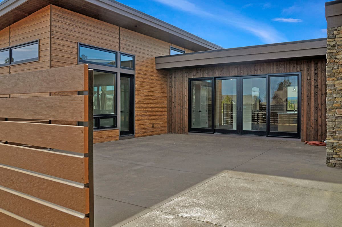 Modern house plan exterior with horizontal wood siding, large windows, and sliding glass doors.