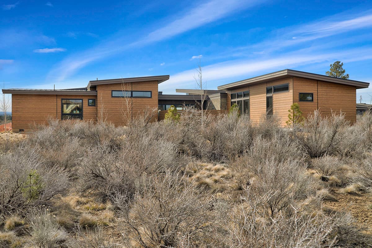 Modern ranch house plan exterior with wood siding, horizontal windows, and angled rooflines.