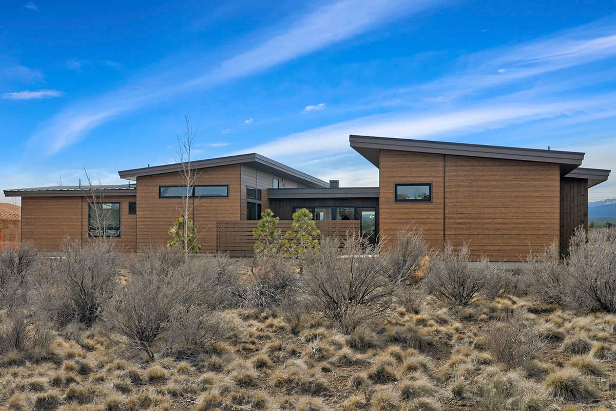 House plan exterior with modern style, wood siding, low-pitched roofs, and horizontal windows.