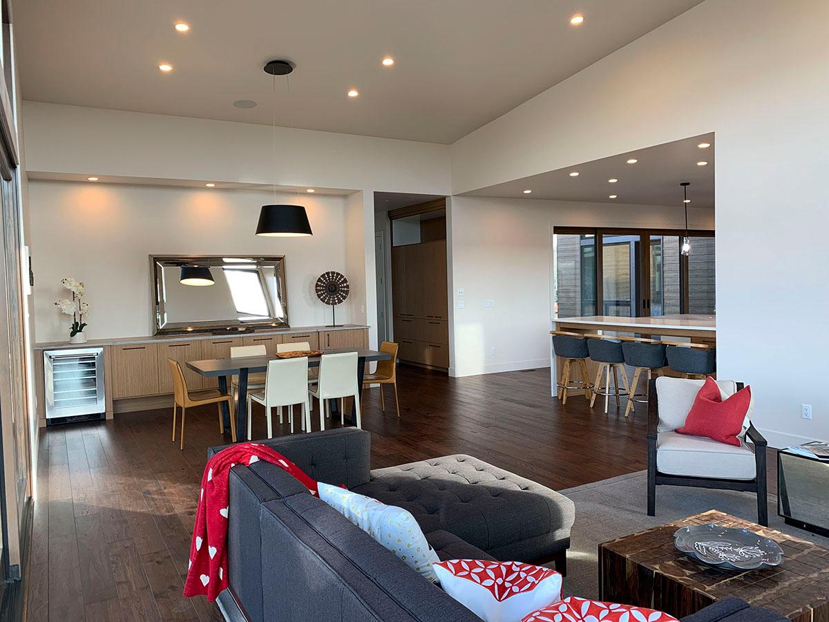 Open concept living area with dining, kitchen island with bar stools, and a sitting area with contemporary furniture.