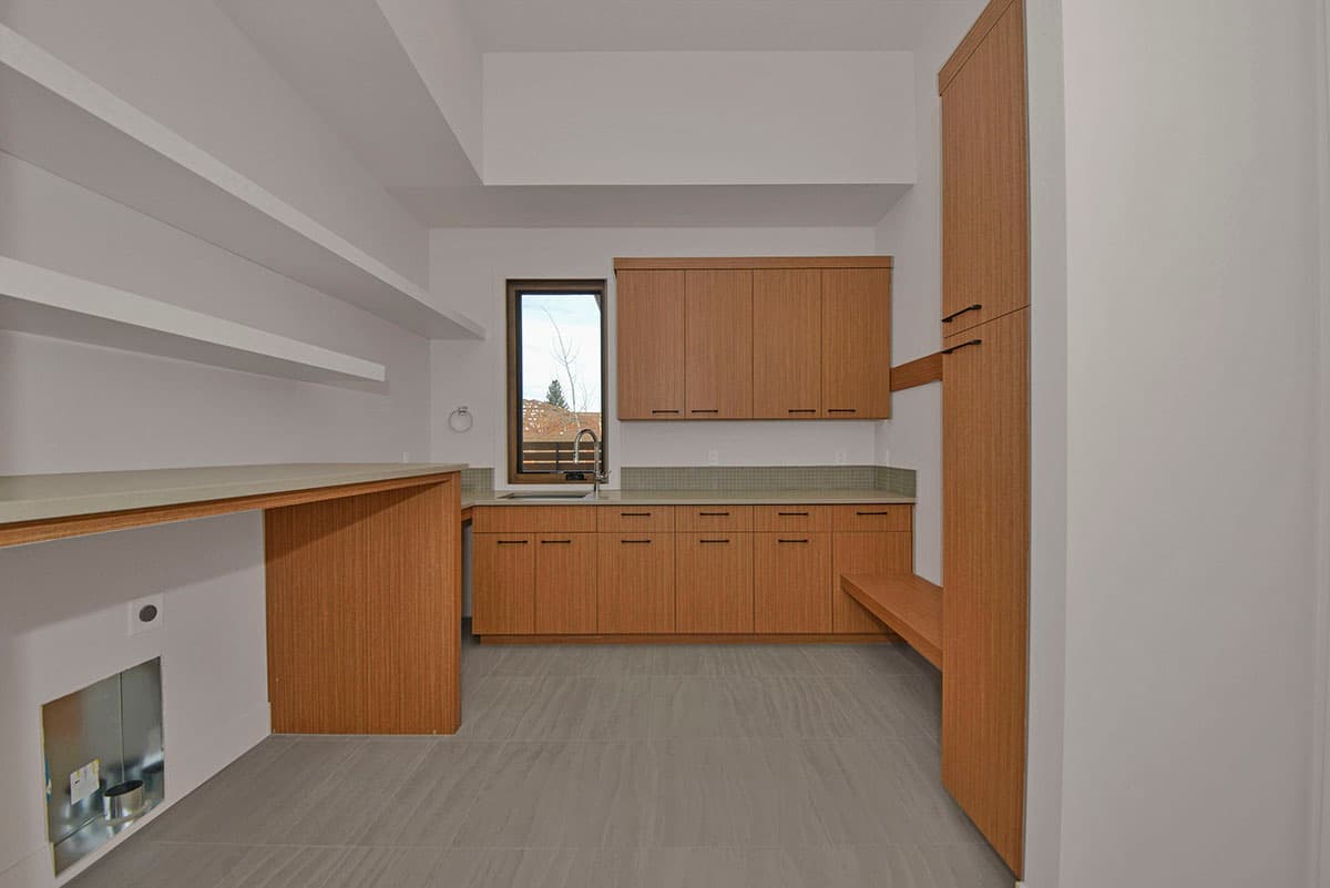 Mudroom with wood cabinetry, built-in bench, sink, counter space, and utility hookups.
