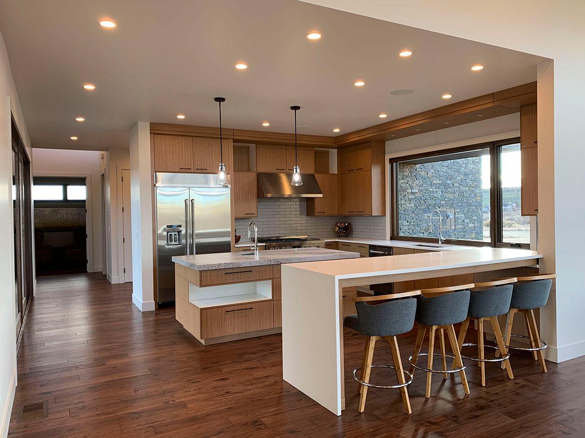 Modern kitchen with light wood cabinetry, stainless steel appliances, island, and breakfast bar with seating.