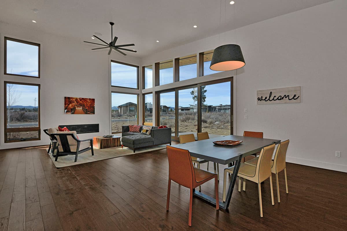 Open concept living and dining area with high ceilings, fireplace, and floor-to-ceiling windows.