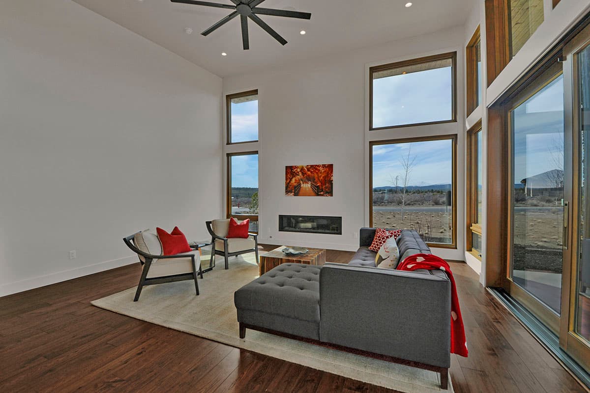 Modern living room with vaulted ceiling, linear fireplace, and floor-to-ceiling windows.