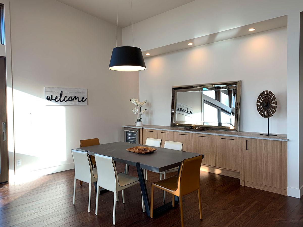 Dining room with dark table, chairs, and built-in wood cabinetry topped with a large mirror.