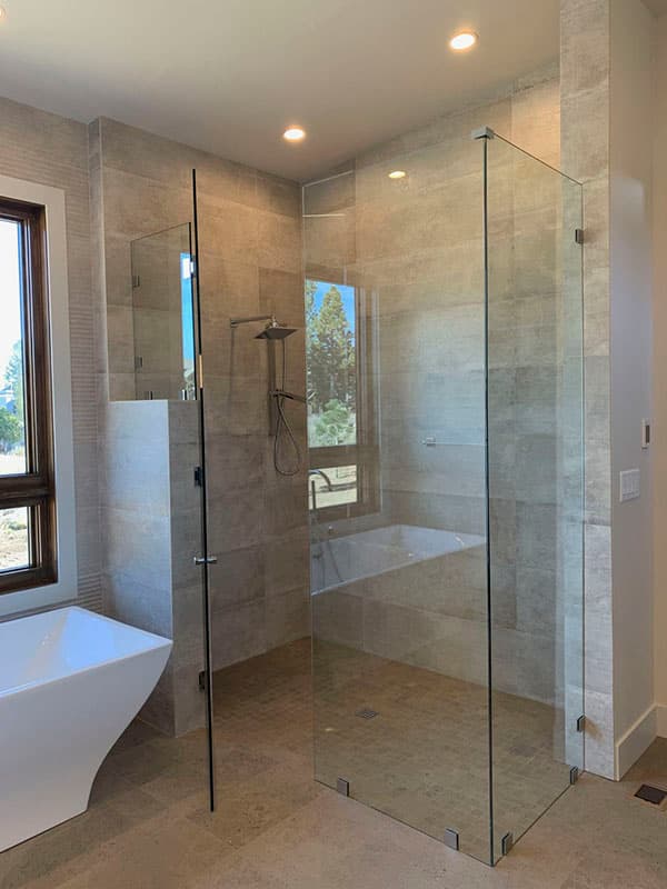 Modern bathroom with freestanding tub, frameless glass shower enclosure, dual shower heads, and tiled walls.