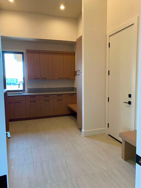 Mudroom with extensive wood cabinetry, built-in bench, and large format tile flooring.