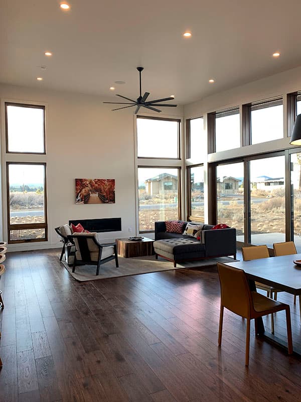 Modern living room with floor-to-ceiling windows, fireplace, sectional sofa, and dining area.