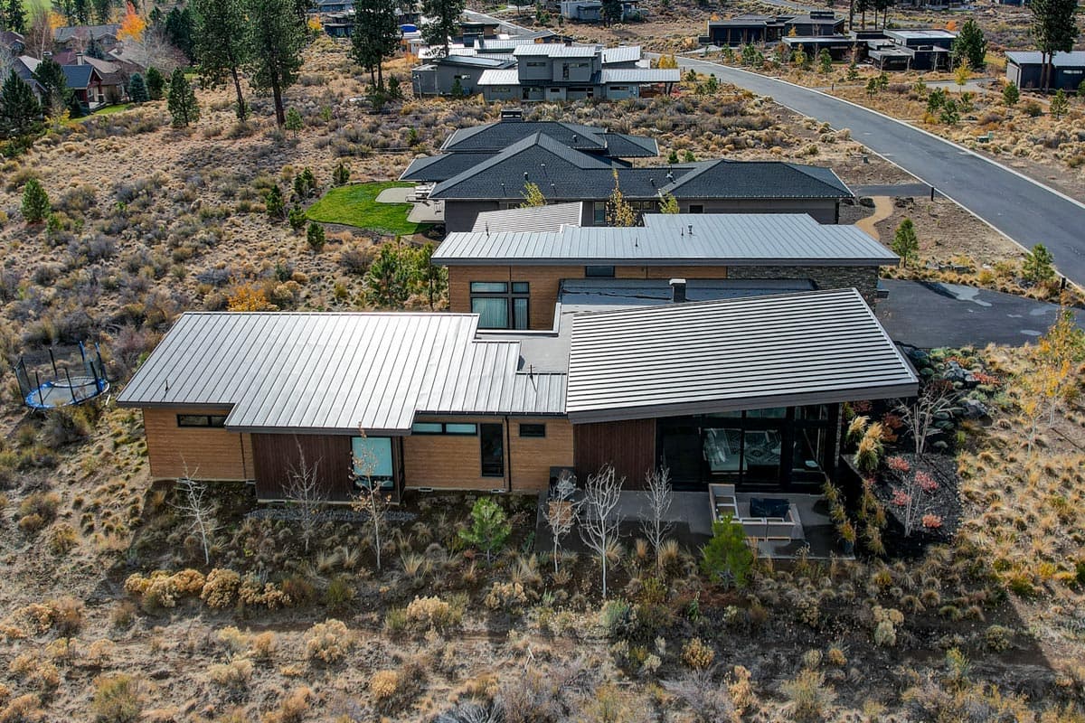 Modern house plan exterior with multiple metal rooflines, wood siding, and expansive windows.