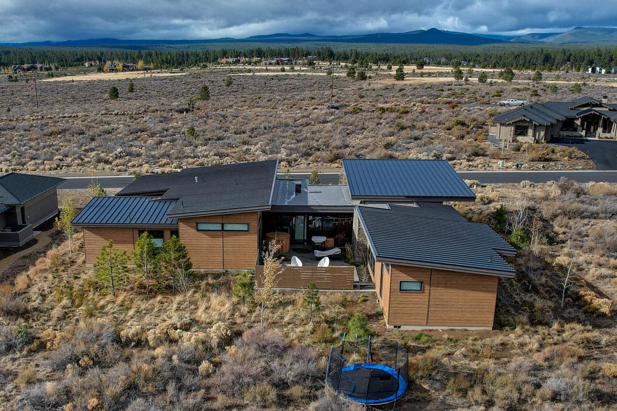 House plan exterior with a modern architectural style, wood siding, and multiple gabled roofs.