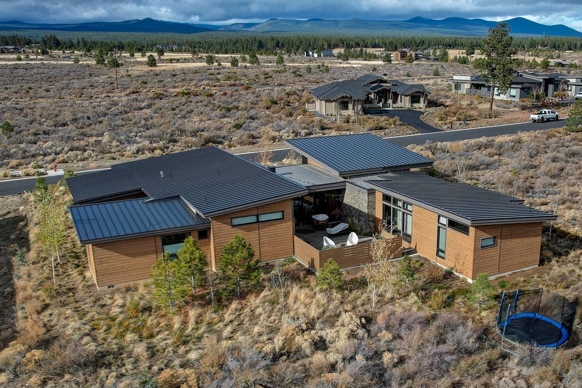 Modern house plan exterior with wood siding, dark metal roofs, and prominent flat rooflines.