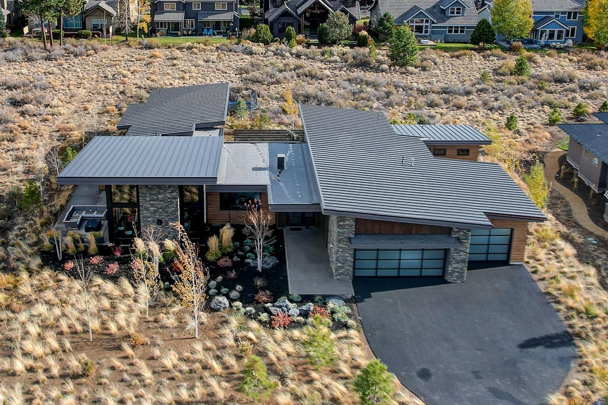 Modern house plan exterior with a multi-level roof, stone and wood facade, and a three-car garage with glass doors.