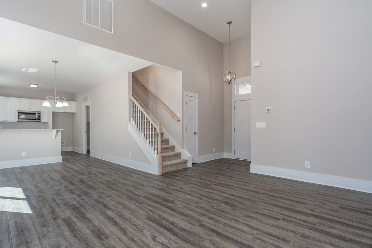 Interior view of house plan: open living space with vaulted ceiling, stairs, kitchen counter, and front door.