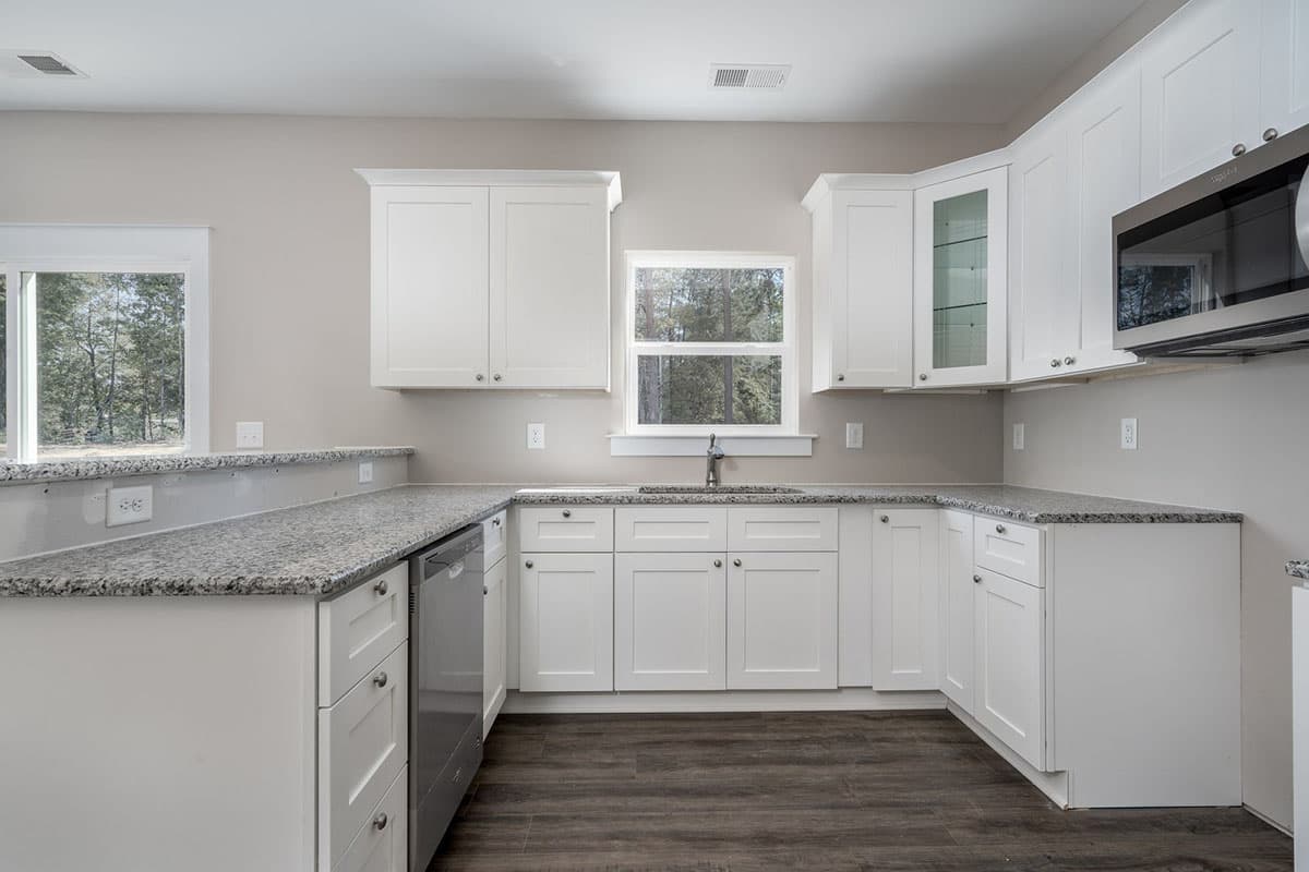 Kitchen with white cabinetry, granite countertops, stainless steel appliances, and dark wood-look flooring.