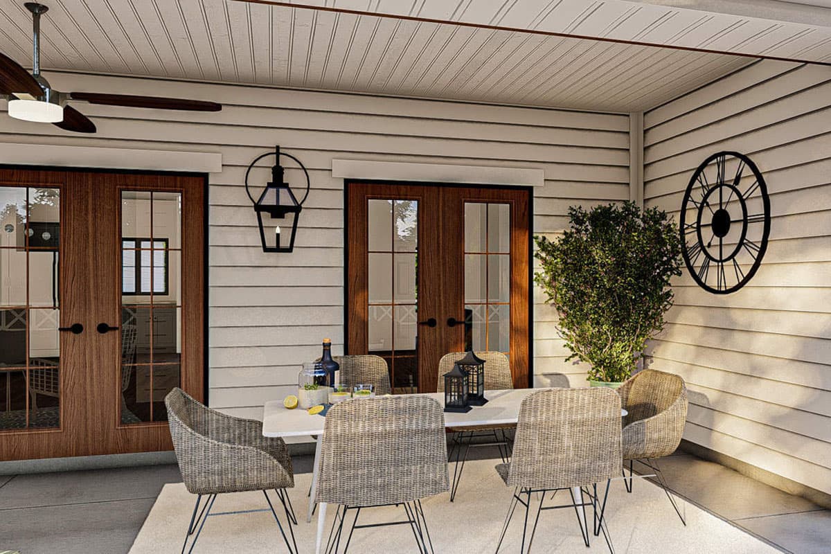 House plan exterior showing a covered porch with double French doors, a ceiling fan, and outdoor dining set.