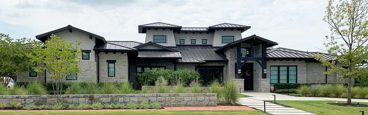 House plan exterior: Modern style with stone and stucco facade, multiple gables, dark metal roof, and prominent entryway.