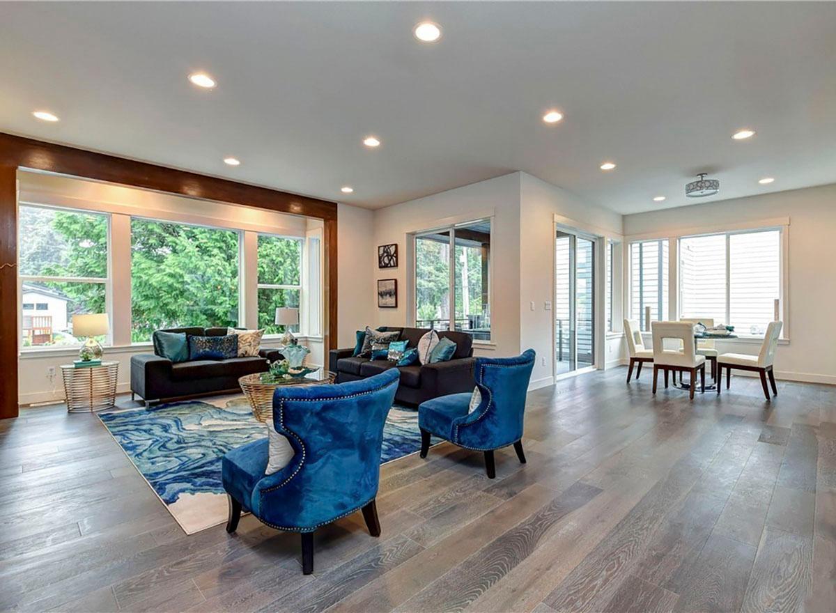 Open concept living and dining area with large windows, recessed lighting, and dark wood flooring.