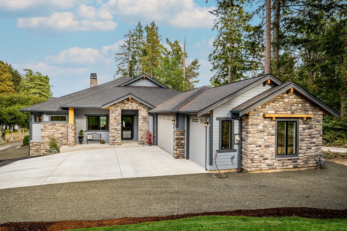 House plan exterior. Single-story Craftsman home with stone accents, gabled roof, and attached garage. Includes covered entry and a concrete driveway.