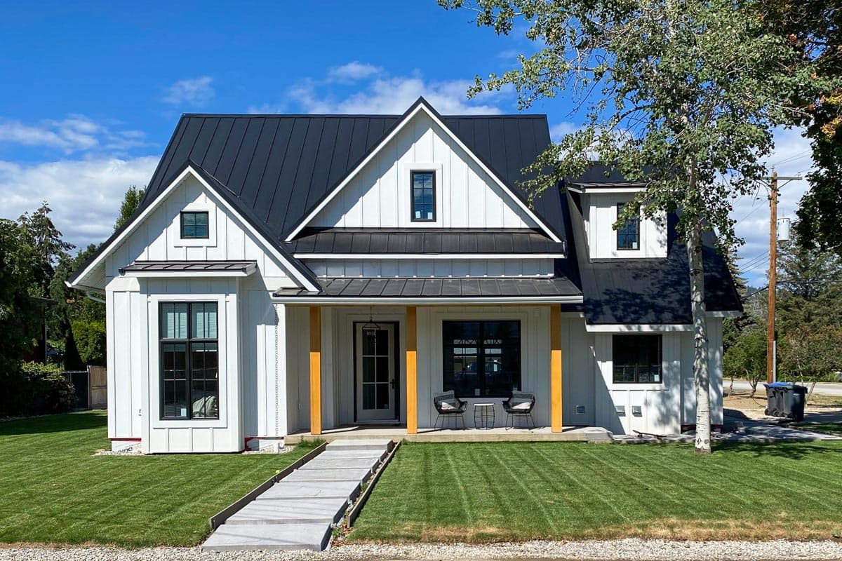 Modern Farmhouse house plan exterior with a black metal roof, board and batten siding, and a covered front porch with wood posts.
