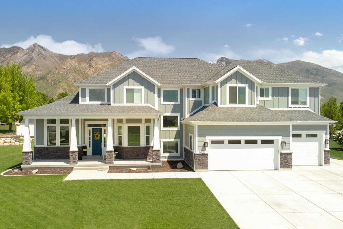 House plan exterior. Two-story home with Craftsman-style elements. Features include a front porch with columns, multiple gables, and a two-car garage.