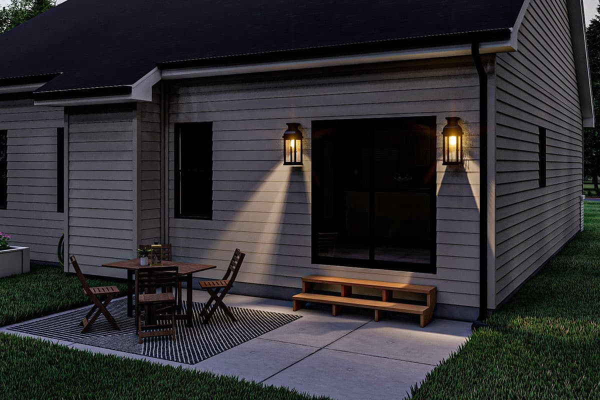 House plan exterior with horizontal siding, gabled roof, two lantern sconces, and patio seating area.
