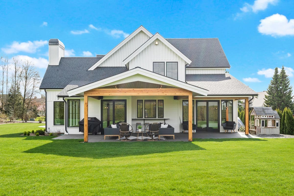 Modern Farmhouse house plan exterior with two stories, white siding, gables, and a covered patio with wooden beams.