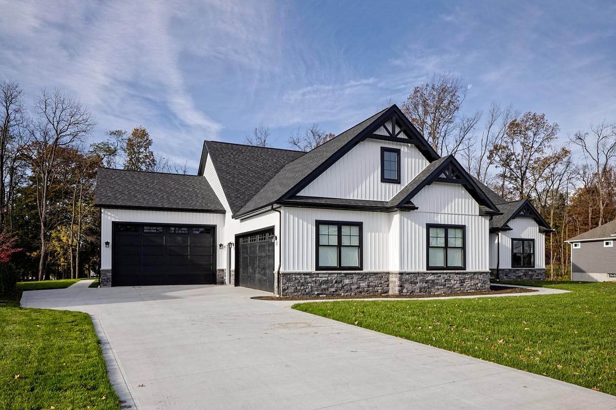 Modern Farmhouse house plan exterior with white board-and-batten siding, stone accents, black-framed windows, and a three-car garage.