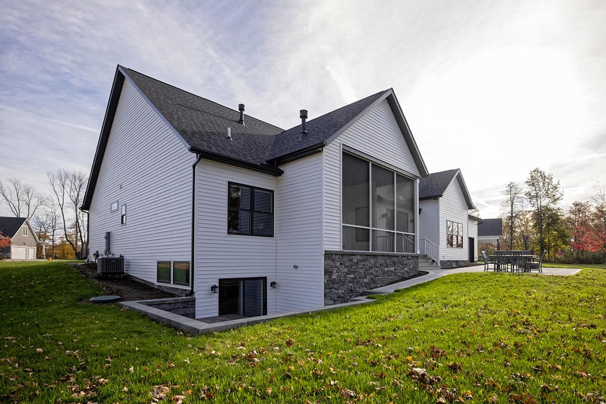 Modern Farmhouse house plan exterior with white siding, stone foundation, screened porch, and multiple gables.