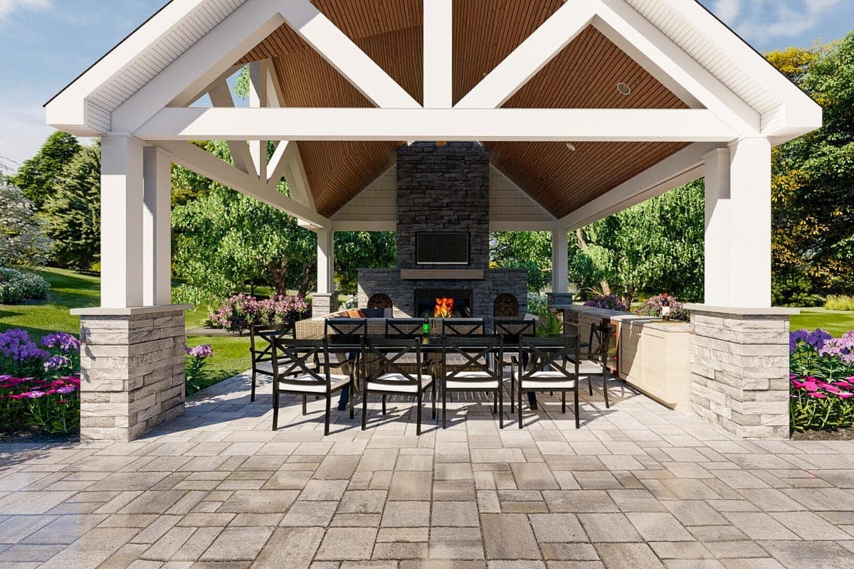 Open-air pavilion with vaulted wood ceiling, stone fireplace, outdoor dining set, and bar area.